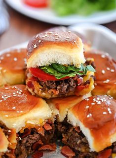 several hamburgers with meat and cheese on them are stacked up in a white plate