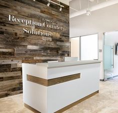 the reception counter is white and brown with wood paneling on the wall behind it