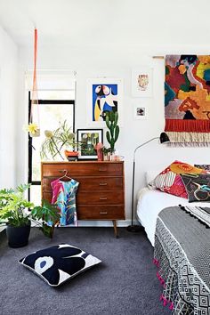 a bedroom with a bed, dresser and paintings on the wall