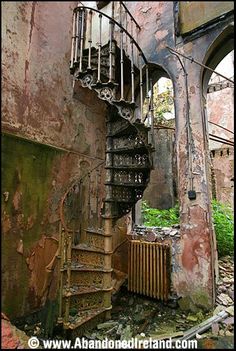 an old spiral staircase in the middle of a run down building