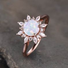 an opal and diamond ring on top of a stone surface with the sun in the middle