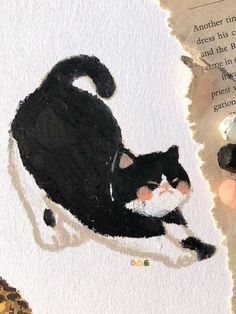 a black and white cat sitting on top of a piece of paper next to a book