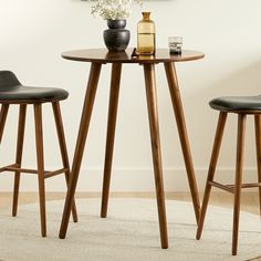 a round table with two stools in front of it and a painting on the wall