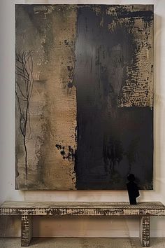 an abstract painting is displayed on a wall with a bench in the foreground and a black vase next to it