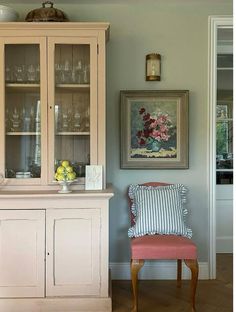 a white china cabinet sitting next to a red chair