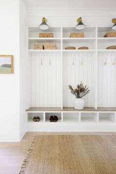 an entryway with white shelves and baskets on the top shelf, along with shoes