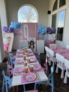 a table set up for a birthday party with pink and blue balloons on the wall