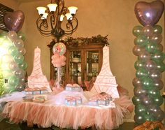 a table set up for a party with pink and green balloons