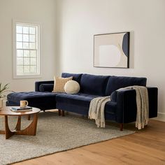 a living room with a blue couch and coffee table on the floor next to a window