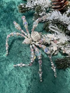 a close up of a spider on a green cloth with pine cones and other decorations