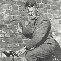 a man riding on the back of a bike next to a brick wall