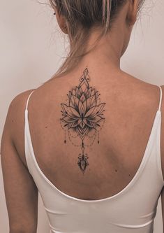 a woman with a tattoo on her back is looking down at the camera while wearing a white tank top