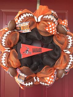 an orange and black football wreath is hanging on a door with the team's name