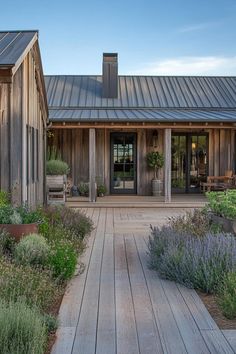 a wooden house with a metal roof and lots of greenery on the front porch