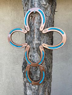 a pair of scissors hanging from a tree branch with blue and brown rings attached to it