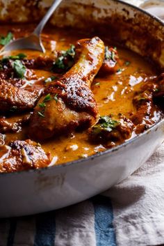 a pan filled with meat covered in sauce and garnished with parsley