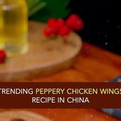 a wooden cutting board topped with chicken wings next to a bottle of pepperoni oil