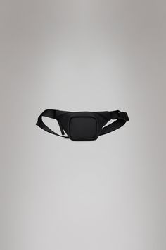 a black fanny bag hanging from the side on a gray background with no one in it