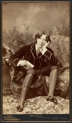 an old fashion photo of a man sitting on a chair with his hand to his face