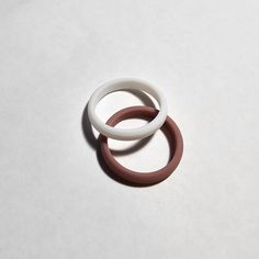 two white and brown rings sitting on top of a table next to each other with one red ring in the middle