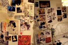 a wall covered in pictures and papers next to a bed