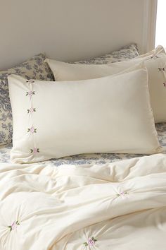 a bed with white sheets and pillows on top of it