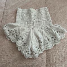 a pair of white shorts with crochet on them laying on a carpeted floor