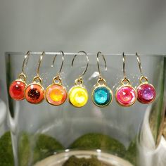 "Choose from one of 7 designs: One of a kind clay (red with scarlet, red with fire opal, yellow with sunshine, turquoise with laguna delite, purple with burgundy, orange with orange glow and cherry vanilla blend with royal red delite) and resin (creates a glass like finish) dangling earrings. Embellished with an embedded austrian crystal (6.2mm chatons) in a 15x11mm gold plated pewter bezel. Approximate length 1\". Hung on gold filled end ball ear wires. Photos taken in studio light.  Free U.S. Colorful Round Earrings Gift, Colorful Round Earrings For Gift, Vibrant Drop Earrings Jewelry Gift, Vibrant Drop Earrings For Gift, Vibrant Drop Earrings For Gifts, Modern Rainbow Jewelry For Gifts, Modern Rainbow Jewelry For Gift, Modern Rainbow Colored Jewelry For Gifts, Modern Rainbow Jewelry Gift