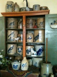 a shelf filled with lots of vases on top of a wooden table next to a wall