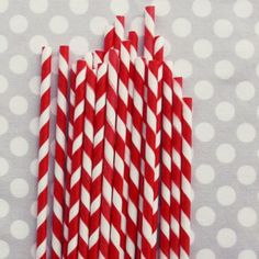 red and white striped paper straws are lined up on a polka dot tablecloth