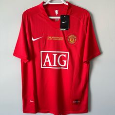 a red shirt hanging on a hanger with the word aig printed on it