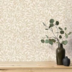 two vases with plants in front of a wallpapered background that looks like leaves