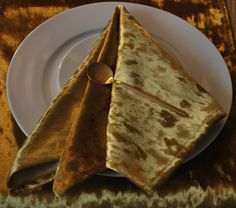 a white plate topped with two gold colored napkins