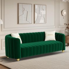 a green velvet couch with two white pillows on it in a living room area next to a rug