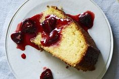 a piece of cake on a white plate with cherries and cranberry sauce