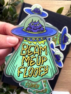 a hand holding up a sticker that says beam me up floor