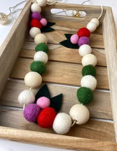 a close up of a wooden tray with beads and felt balls on the bottom, along with an ornament in the middle