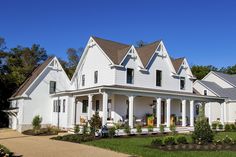 a large white house with lots of windows on it's sides and front porch