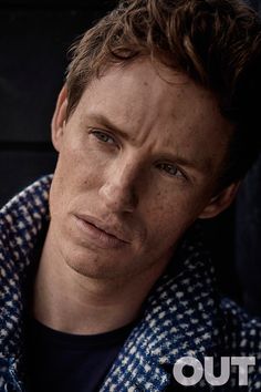 a man with freckled hair and blue eyes looks into the camera while sitting in a car