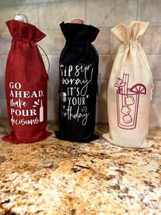 three wine bags sitting on top of a counter next to each other with writing on them