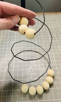 a person is holding some beads on a wire