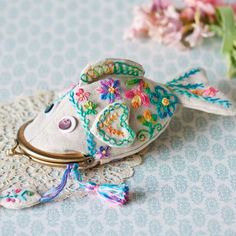 a fish brooch sitting on top of a doily next to some pink flowers