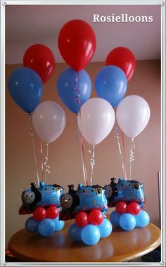 thomas the tank engine birthday cake with balloons and train cars on it's top