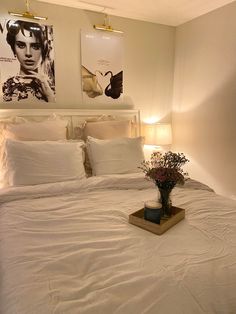 a bed with white sheets and pillows in a bedroom next to two pictures on the wall