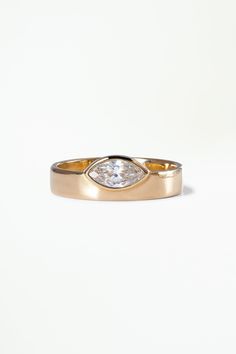 a gold ring with a pear shaped diamond in the center, on a white background