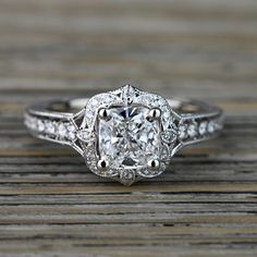 an old - fashioned engagement ring with a cushion cut diamond center surrounded by pave diamonds