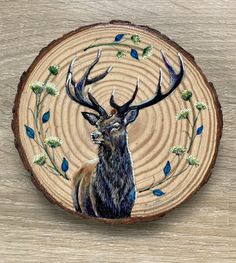 a deer is depicted on a wood slice with flowers and leaves around it, as well as the head of an antelope