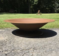 a large brown bowl sitting on top of a cement slab