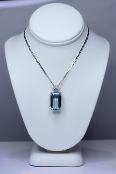 RRV: $17.650 A magnificent natural aquamarine pendant necklace features a large emerald cut aquamarine of 11.05 carats in a four-prong setting with gold design at the base. The bail is centred with a 3mm diamond and surrounded by a delicate halo of 16 diamonds.  The pendant is accompanied by a 50 cm length, 18 carats white gold chain. SPECIFICATIONS: 1982404 Gemstone: Emerald-cut natural Aquamarine. Measures: 16.67 x 9.97 x 8.03. Weight: 11.05 carats. Side Stones:  *1 x 3.0mm round brilliant cut Luxury Elegant Solitaire Gemstone Necklace, Luxury Aquamarine Necklace In Fine Jewelry Style, Luxury Classic Necklace With Rectangular Stone, Elegant Aquamarine Necklace For Formal Occasions, Luxury Light Blue Brilliant Cut Jewelry, Elegant Oval Aquamarine Necklaces, Elegant Oval Aquamarine Necklace, Formal Oval Aquamarine Necklace, Luxury Aquamarine Necklace For Formal Occasions