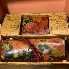 two leather wallets in a box with writing on the wall behind them and flowers painted on it